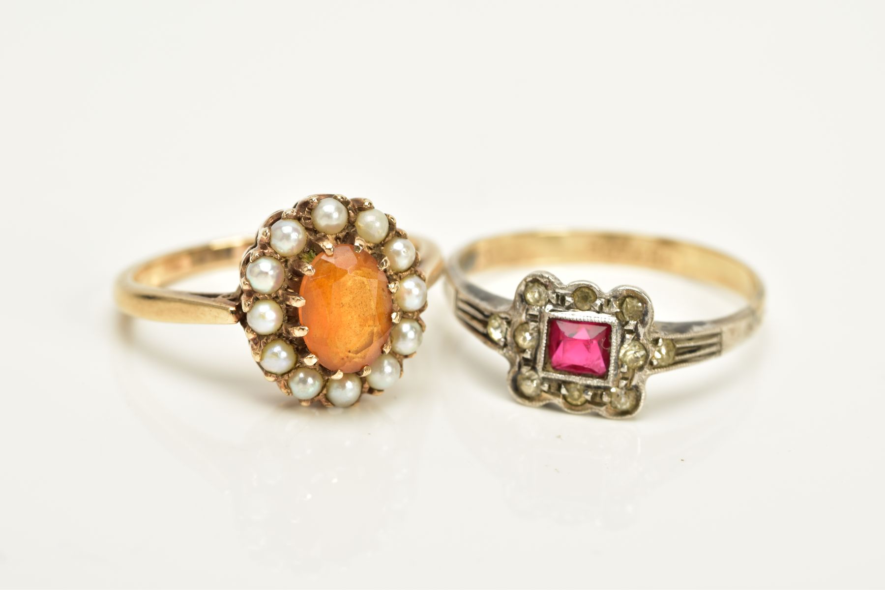 TWO CLUSTER RINGS, the first designed with a central oval cut orange stone assessed as citrine,