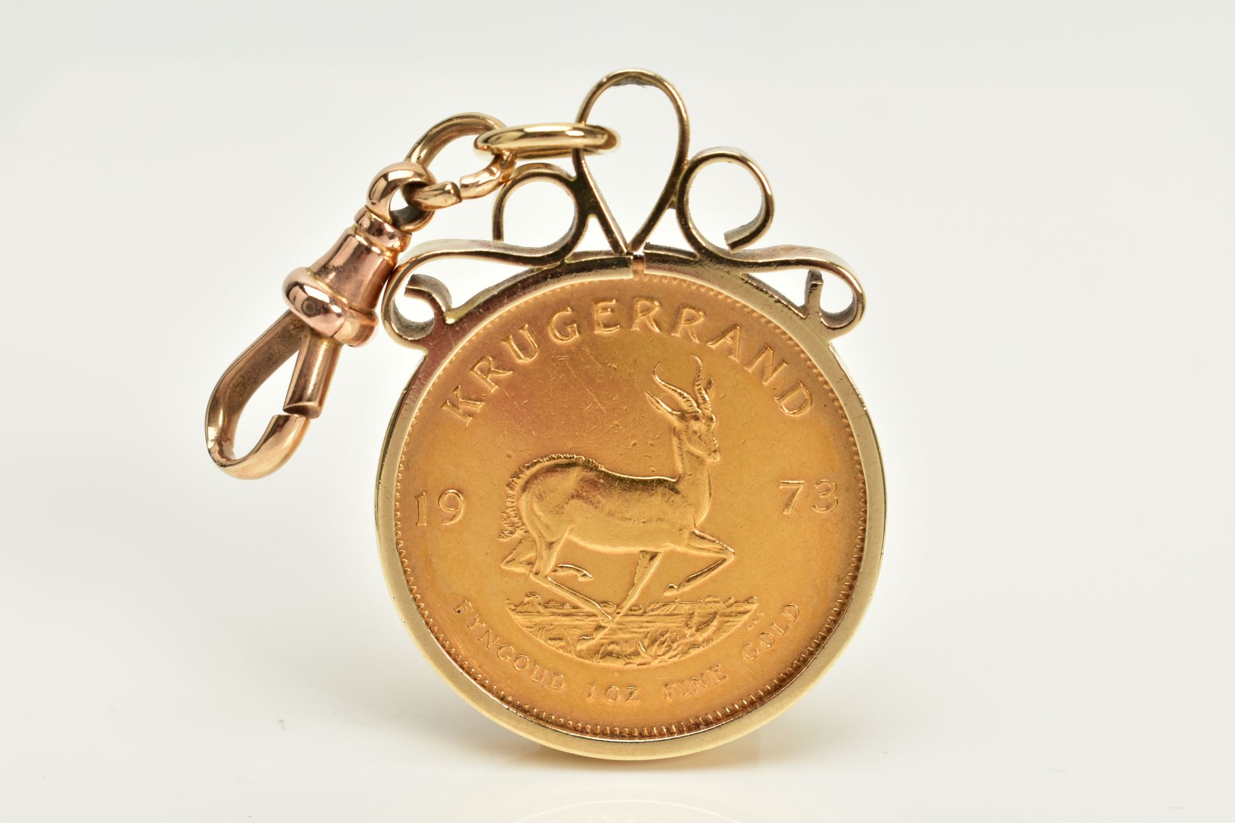 A 1973 KRUGERRAND IN A YELLOW METAL MOUNT, within a yellow metal collet mount of scroll design,