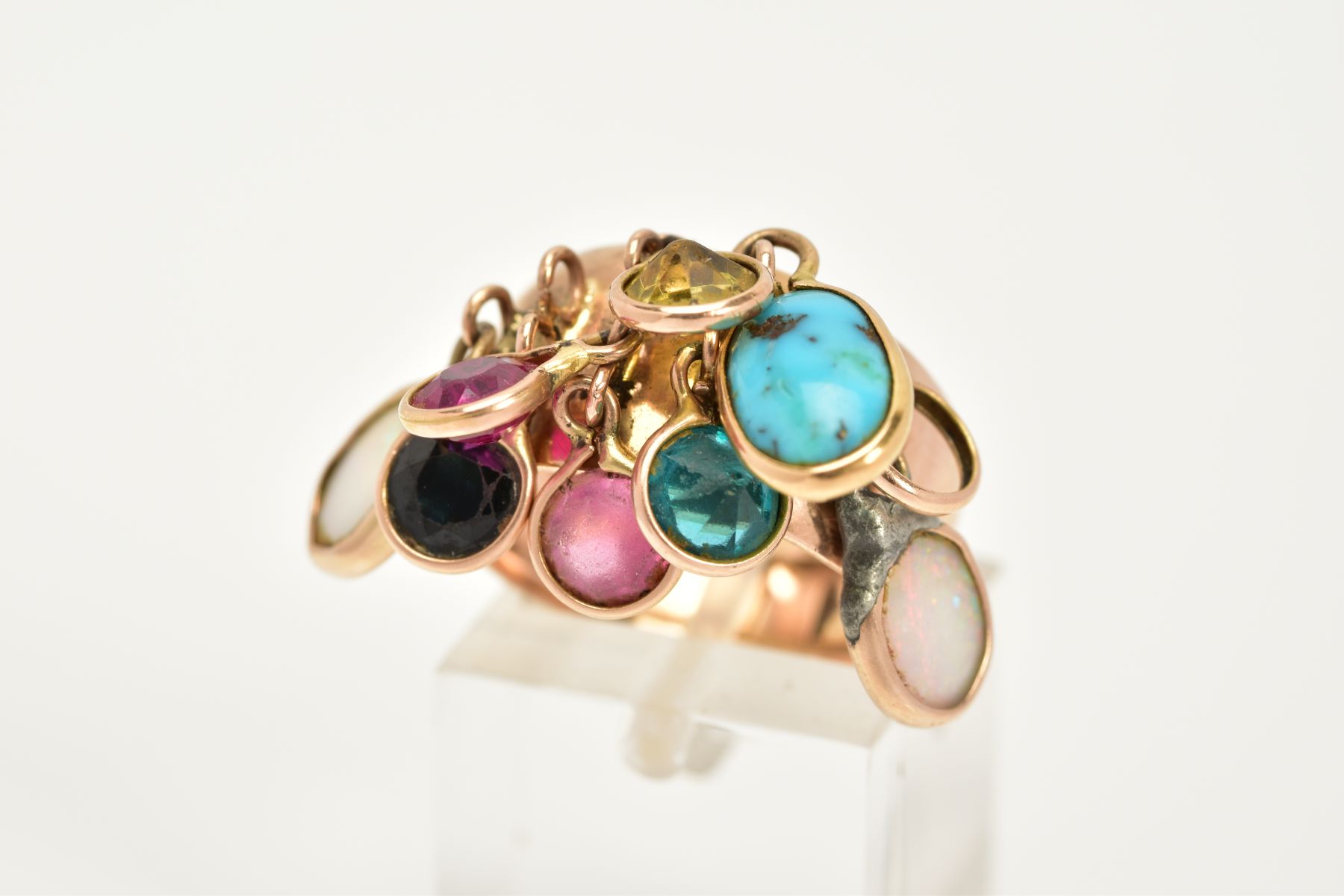 A YELLOW METAL MULTI-GEMSTONE RING, the plain polished wide shank, suspends nine drops containing