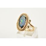 A YELLOW METAL RING, of oval design, set with a broken opal triplet, within a collet mount and
