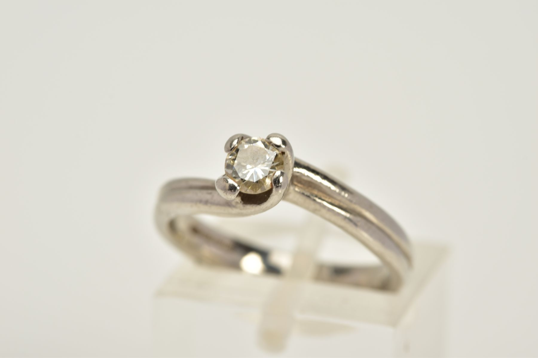 A PLATINUM SINGLE STONE DIAMOND RING, of crossover design, with a claw set round brilliant cut