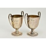 A PAIR OF SILVER DOUBLE HANDLED CUPS, of plain polished design, foliate detailed handles, upon a