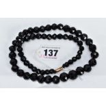 A FACETED JET BEAD NECKLACE, of a graduated faceted bead design, the beads measuring between 7.8-