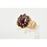 A 9CT GOLD GARNET CLUSTER RING, the raised cluster designed with a central oval cut garnet, within a