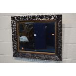 A LATE 19TH CENTURY OAK FRAMED BEVELLED EDGE WALL MIRROR, the frame with depicting carved fruiting