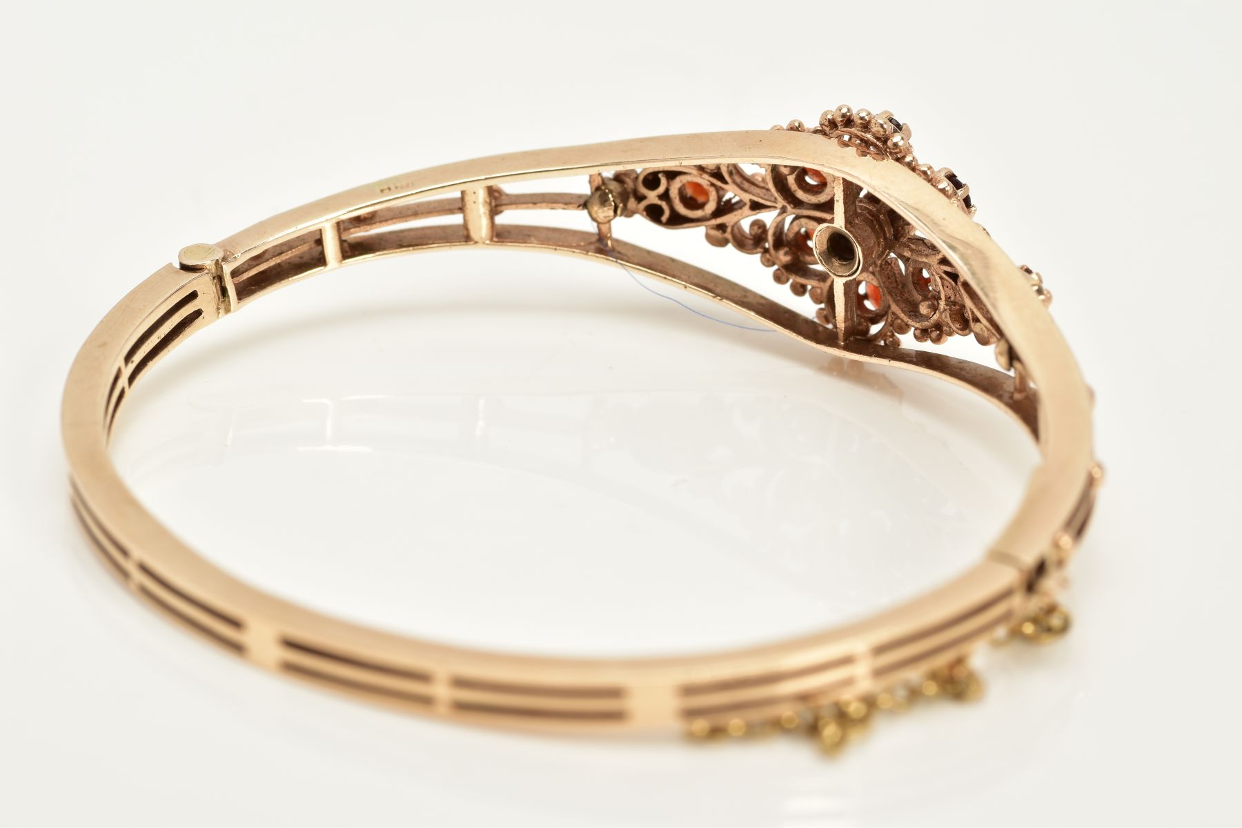 A 9CT GOLD GARNET SET OPENWORK BANGLE, the openwork hinged bangle of floral design, set with - Image 4 of 6