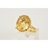 A YELLOW METAL CITRINE RING, designed with a claw set oval cut Citrine, openwork basket designed