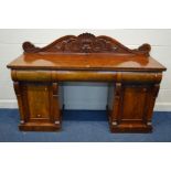 A VICTORAN MAHOGANY PEDESTAL SIDEBOARD, with a raised scrolled back, three various frieze drawers,