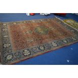 A LATE 20TH CENTURY KERMAN RUG, central medallion on a red field between a multistrap border,