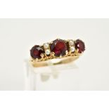 A 9CT GOLD GARNET AND PEARL RING, designed with three circular cut garnets interspaced with seed