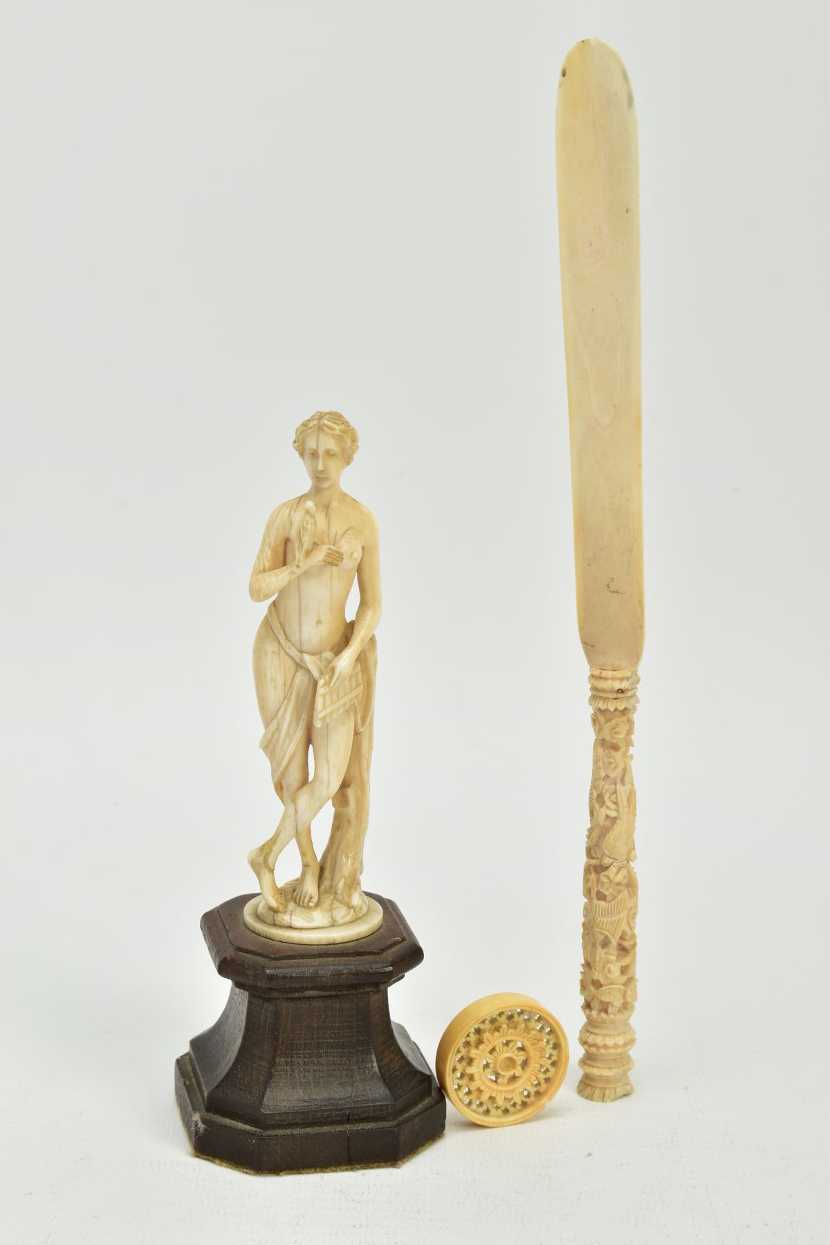 A 19TH CENTURY CARVED IVORY FIGURE OF A SCANTILY CLAD FEMALE WITH A BIRD AND PIPES, mounted on a