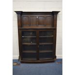 AN EARLY 20TH CENTURY OAK BOOKCASE, having an overhanging cornice, four panels, above a double