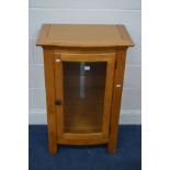 A VARNISHED PINE SINGLE GLAZED DOOR CABINET enclosing two adjustable glass shelves, overhanging