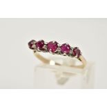 A YELLOW METAL RUBY RING, designed with a row of five circular cut graduated rubies, tapered