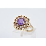 A YELLOW METAL AMETHYST AND SEED PEARL CLUSTER RING, the openwork raised floral cluster, set with