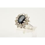 A MODERN SAPPHIRE AND DIAMOND OVAL CLUSTER RING, sapphire measuring approximately 10.2mm x 7.8mm,
