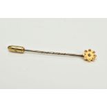 A YELLOW METAL DIAMOND SET STICK PIN, of a flower shape design, with a star set rose cut diamond,