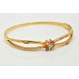 A YELLOW METAL TOPAZ AND DIAMOND BANGLE, the openwork cross over style hinged bangle, set with a