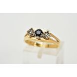 A YELLOW METAL THREE STONE SAPPHIRE AND DIAMOND RING, the raised designed set with a central