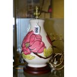 A MOORCROFT POTTERY TABLE LAMP WITH PINK MAGNILIA ON A CREAM GROUND, mounted on a wooden base,