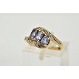 A THREE STONE CROSS OVER RING, designed with three oval cut iolite, within single cut diamond