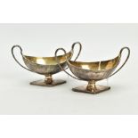 A NEAR PAIR OF GEORGE III STERLING SILVER SALTS, each twin handled oval urn form on a raised lozenge