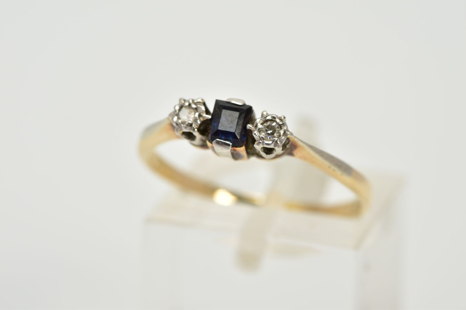 A THREE STONE SAPPHIRE AND DIAMOND RING, the yellow metal ring set with a central square cut