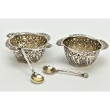 A PAIR OF SILVER SALTS AND SPOONS, each salt with a scroll engraved body, wavy scroll detailed