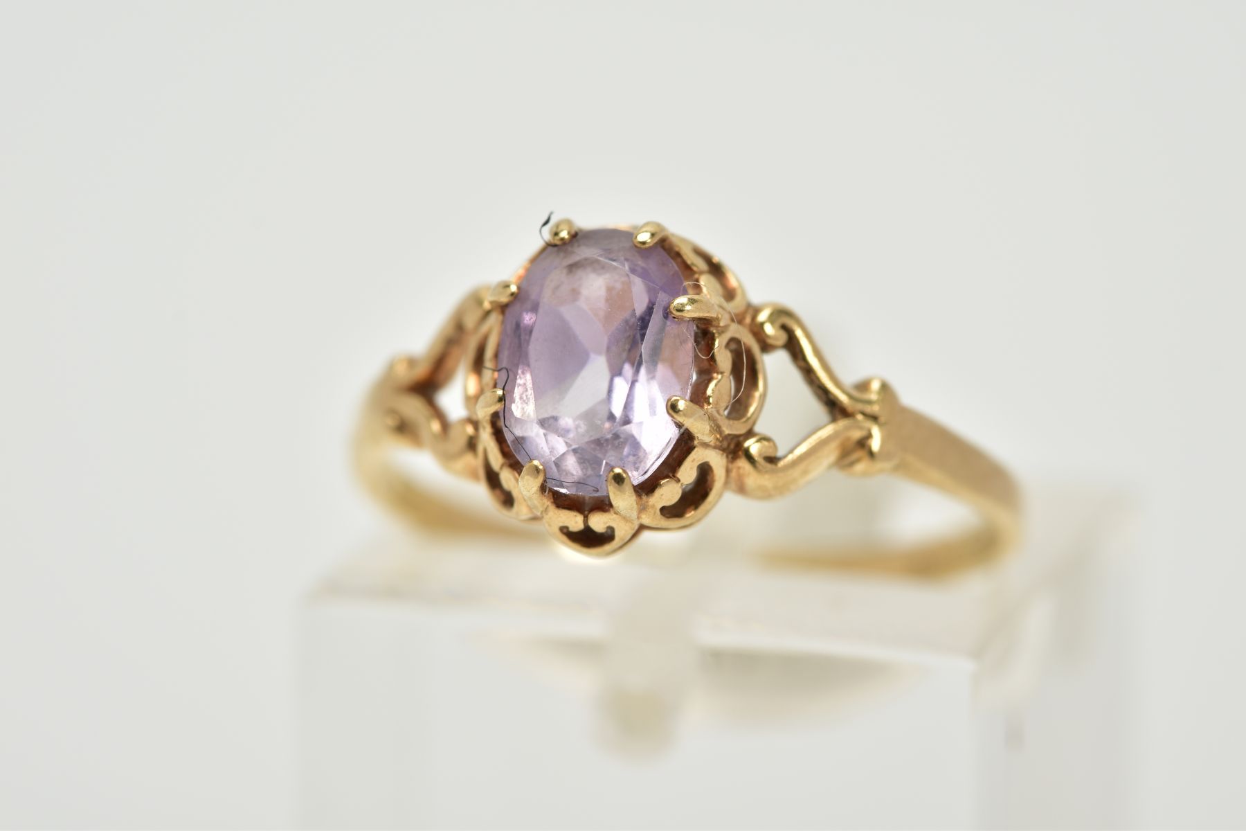 A 9CT GOLD AMETHYST RING, designed with a claw set, oval cut amethyst within an open work gallery,