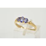 A 14CT GOLD THREE STONE TANZANITE RING, designed with three graduated, oval cut tanzanite stones,