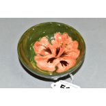 A SMALL MOORCROFT POTTERY FOOTED BOWL, 'Hibiscus' pattern on green ground, impressed backstamp,