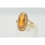 A 9CT GOLD CITRINE RING, designed with an oval cut citrine, within a collet mount and rope twist