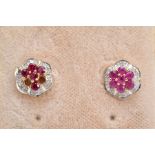 A PAIR OF 9CT GOLD RUBY AND DIAMOND EARRINGS, each of a flower design set with circular cut