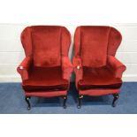 A PAIR OF RED UPHOLSTERED WING BACK ARMCHAIRS (with fire safety label)