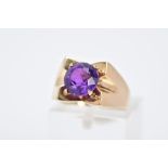 A 9CT GOLD AMETHYST RING, designed with a central claw set, circular cut amethyst within a