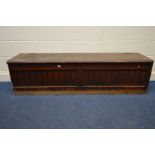 A LONG 19TH CENTURY STAINED PITCH PINE SCHOOL TUCK/STORAGE BOX/BENCH, with double panelled plank