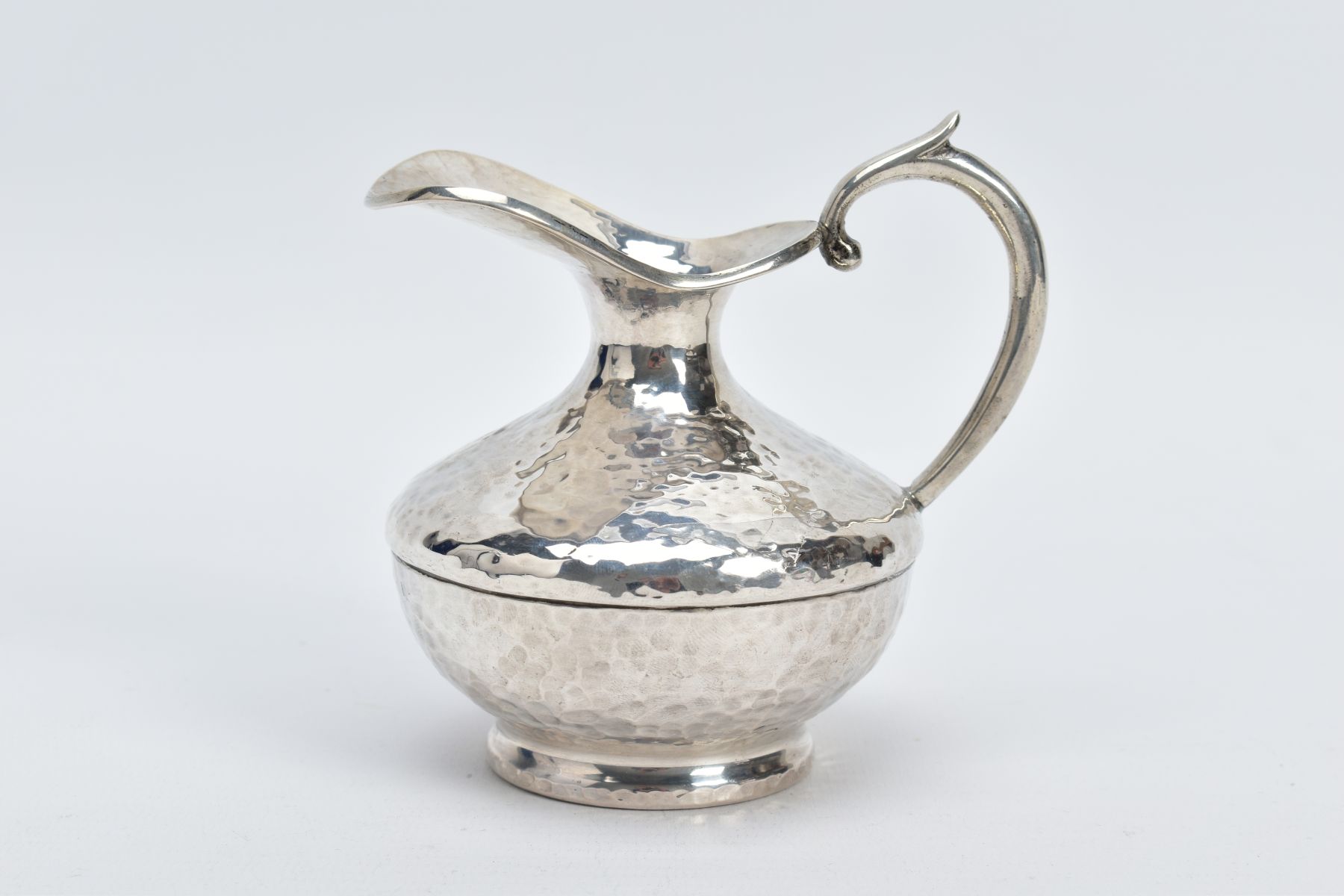 A WHITE METAL JUG, of a hammered design, scroll handle, stamped 925 to the base, approximate gross