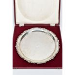 A CASED SILVER SALVER, of a plain polished circular form with a shell decorated wavy edge,