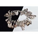 A SILVER CHARM BRACELET, suspending twenty white metal charms, such as a caravan which opens to
