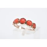 A YELLOW METAL CORAL RING, designed with five graduated coral cabochons, bifurcated textured