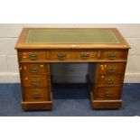 AN EARLY TO MID 20TH CENTURY GREEN LEATHER AND GILT TOOLED PEDESTAL DESK, with nine assorted