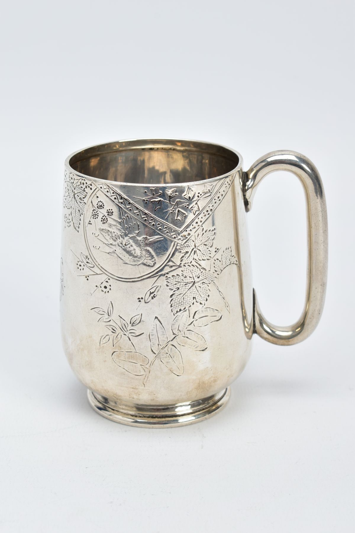 A VICTORIAN SILVER MUG, with a floral and foliate engraved design body, plain polished handle, on