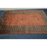 A G H FRITH RUG, with an orange field and foliate border, 239cm x 157cm