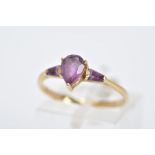 A 9CT GOLD AMETHYST RING, designed with a claw set, pear cut amethyst, flanked by tapered cut