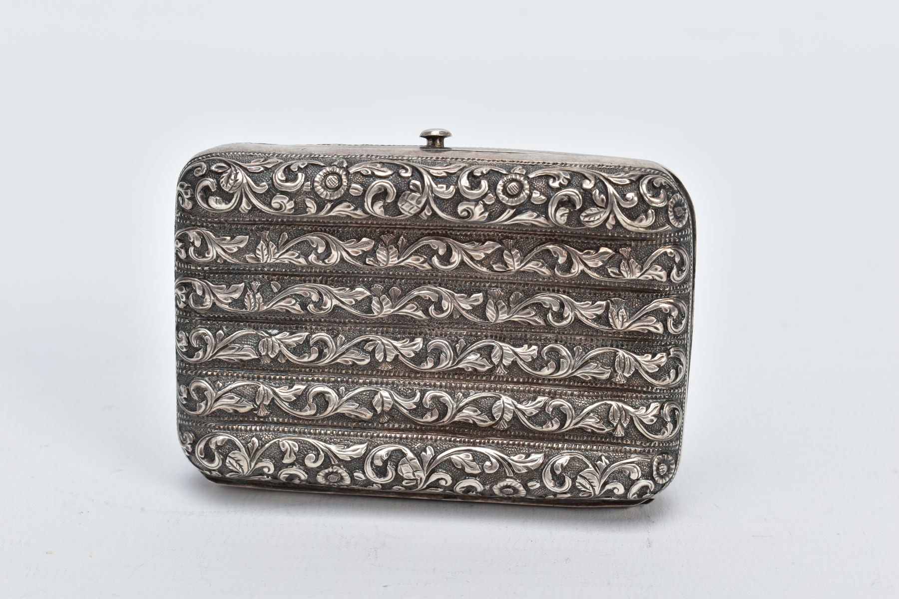 A WHITE METAL ORNATE CASE, of a floral and foliate embossed design, fitted with a push button clasp,