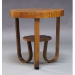 An Art Deco walnut two tier occasional table, c.1930, the circular quarter veneered top on curved