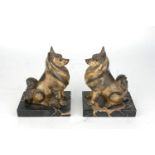 A pair of Art Deco gilded spelter dogs, early 20th century, modelled seated, on rectangular black