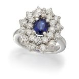 A sapphire and diamond cluster ring, the oval sapphire in claw mount to a brilliant-cut diamond