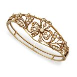 An Edwardian gold and half-pearl bangle, of hinged open hoop design, the tapered front with