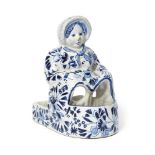 A tin glazed blue and white earthenware figure of a lady, 19th century, modelled seated in a bath,